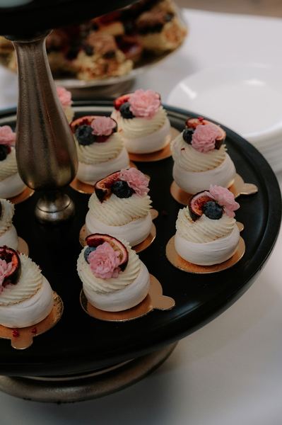 Mini pavlovas with cream and fresh fruit on a wedding dessert table