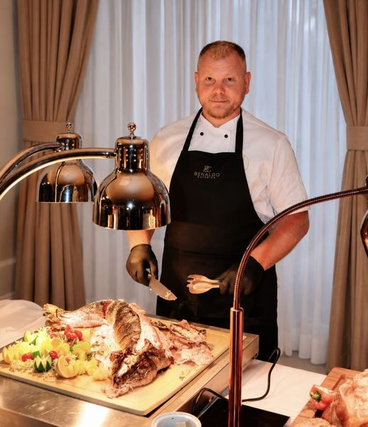 Chef carving roast fish at the hot buffet