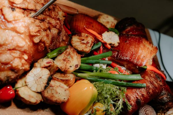 Roast pork knuckle and vegetables on a wooden board