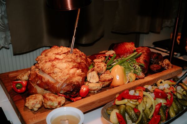 Roast meat on a wooden board with grilled vegetables and pickles